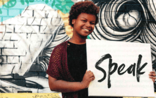 Child in front of graffiti with speak board for Detroit Hour