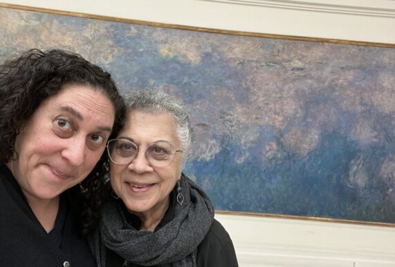 Suma and her mom post smiling in front of a Monet painting in Paris.