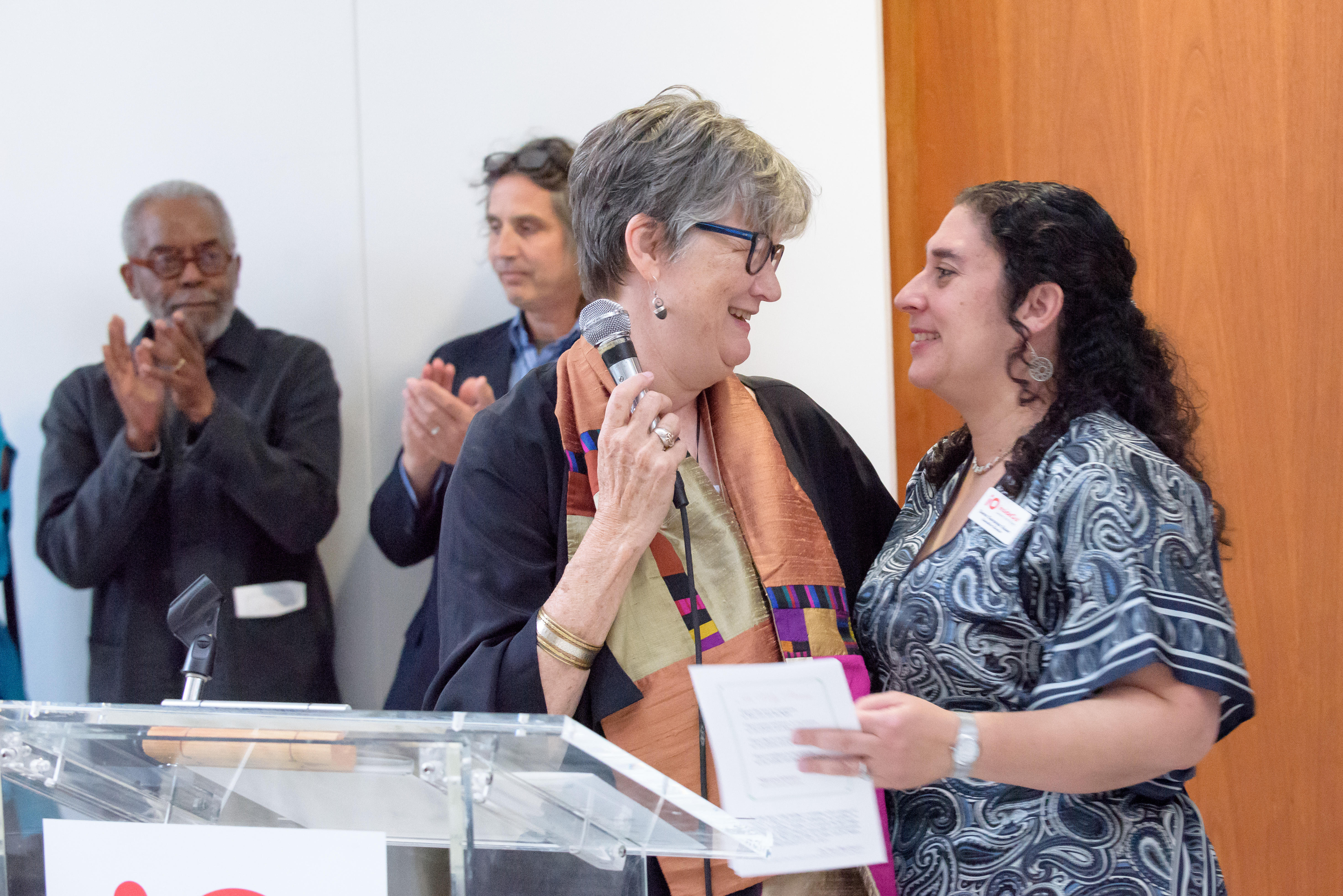 Dr. Terry Blackhawk and Suma hug next to a podium at InsideOut's Share the Light gala.